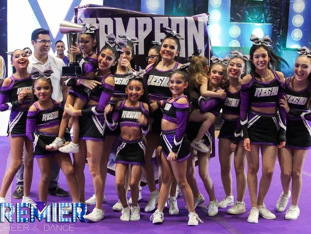 Equipo Regio Cheer celebrando con trofeo y banner de campeón